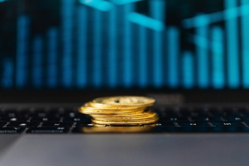 Gold cryptocurrency coins resting on a laptop keyboard with a trading chart in the background