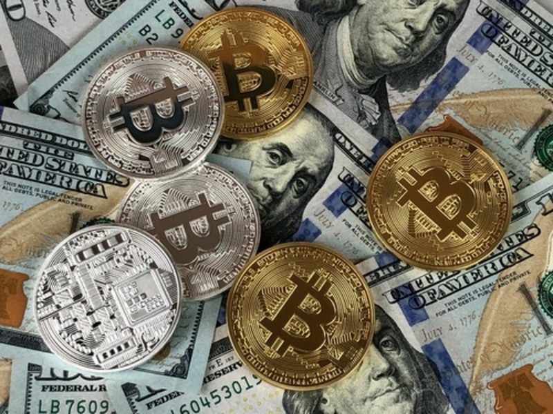 Bitcoin cryptocurrency coins placed on US dollar banknotes